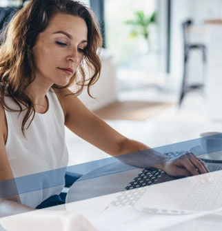 woman reading documents while typing on a laptop
